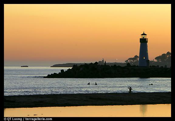 Lighthouse and Surfers in the water at sunset. Santa Cruz, California, USA